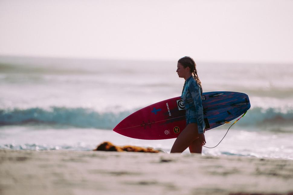 Free Image of Woman Walking on the Beach With a Surfboard 