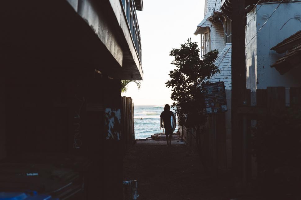 Free Image of Person Walking Down Street Next to Water 