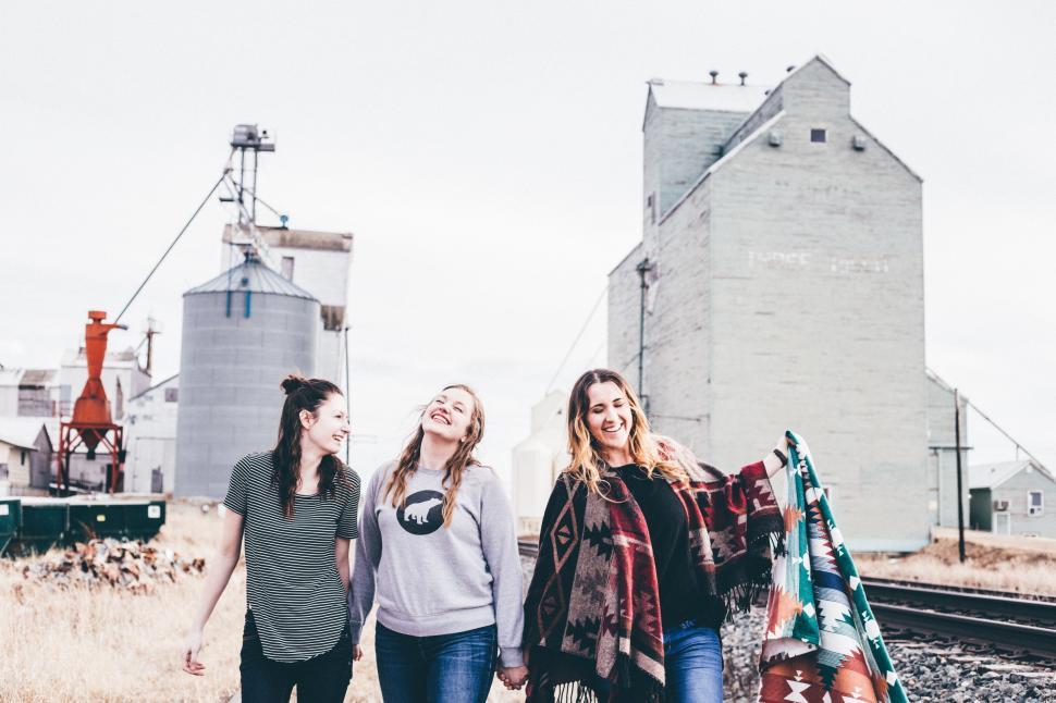 Free Image of Three Women Walking Along Train Track Next to Grain Silo 