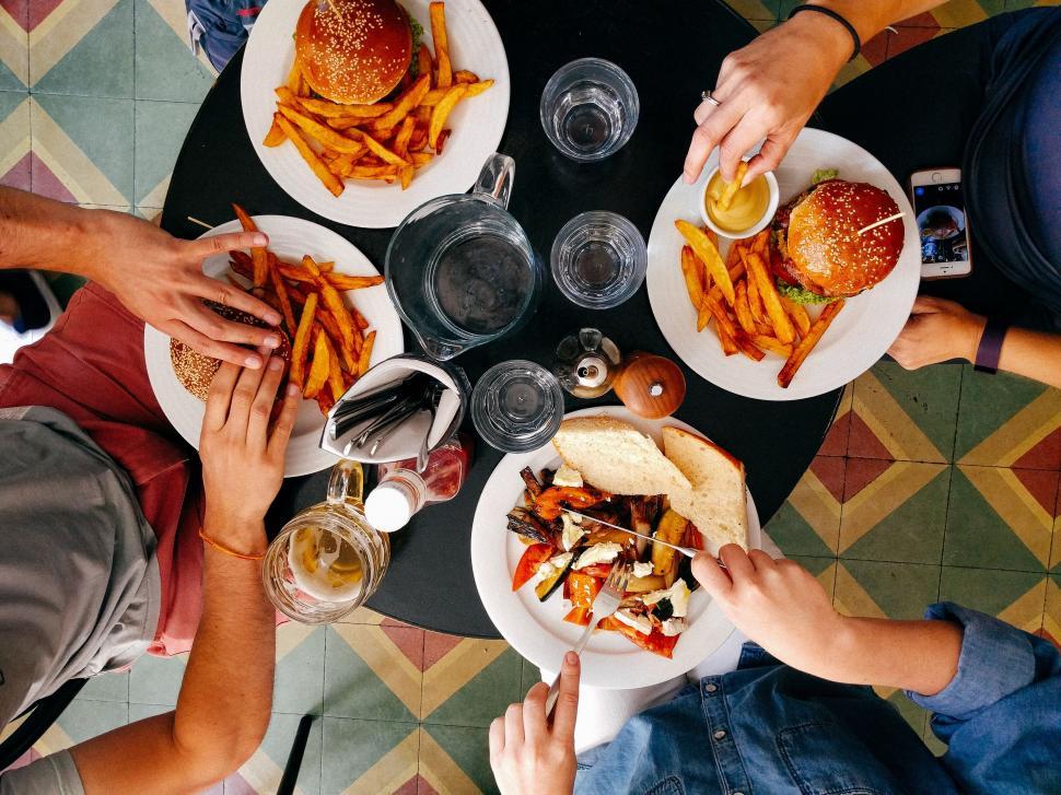 Free Image of Group of People Sitting Around Table Eating Food 