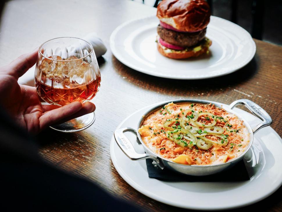Free Image of Person Holding Glass of Wine in Front of Plate of Food 