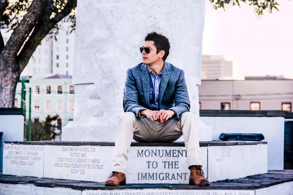 Free Image of Man Sitting on Monument in Front of Tree 