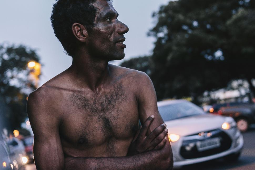Free Image of Shirtless Man Standing in Front of Car 