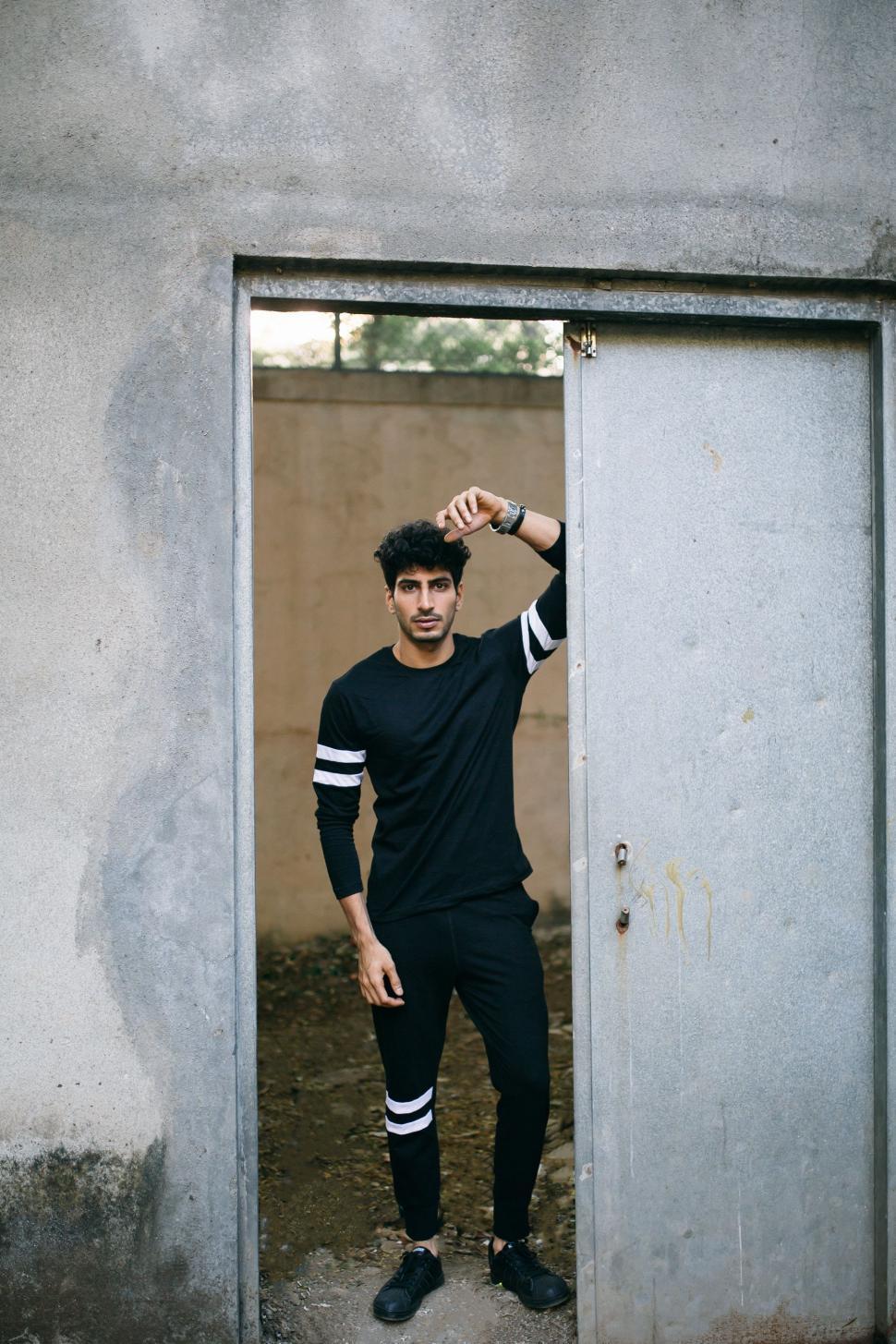 Free Image of Man Standing in Doorway With Hand on Head 
