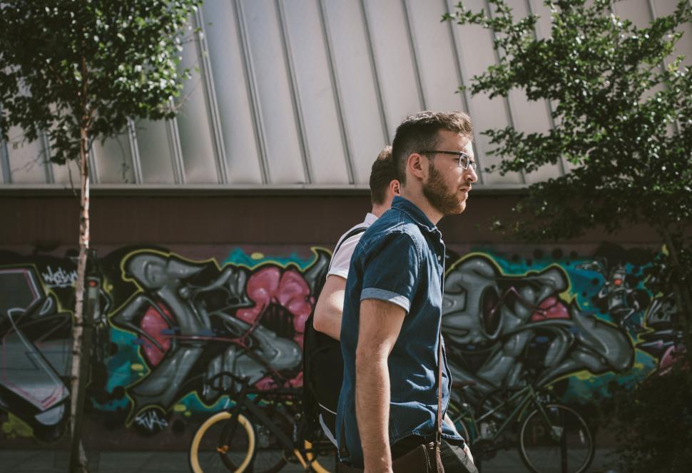 Free Image of Man Walking Down the Street With a Skateboard 