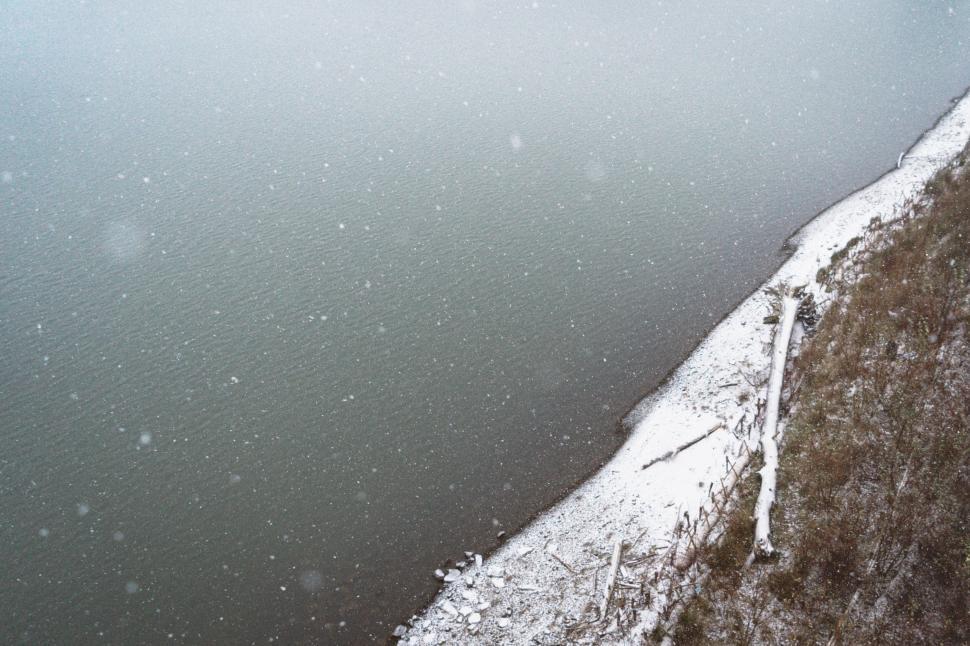 Free Image of Snow Covered Cliff Next to Body of Water 