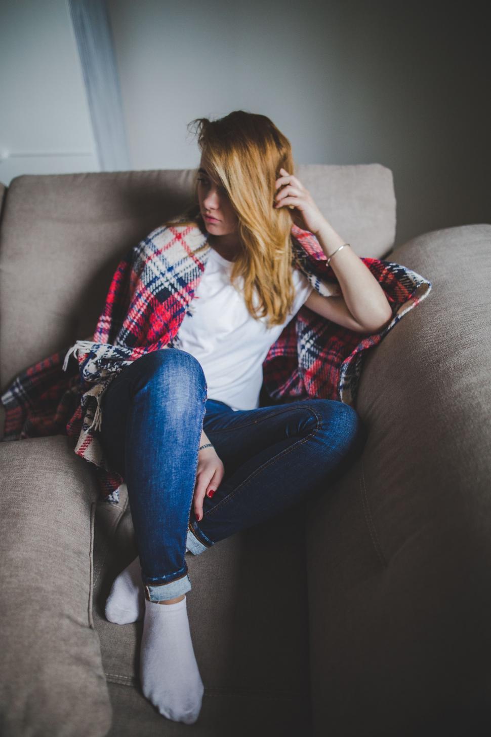 Free Image of Woman Sitting on Couch, Playing With Hair 