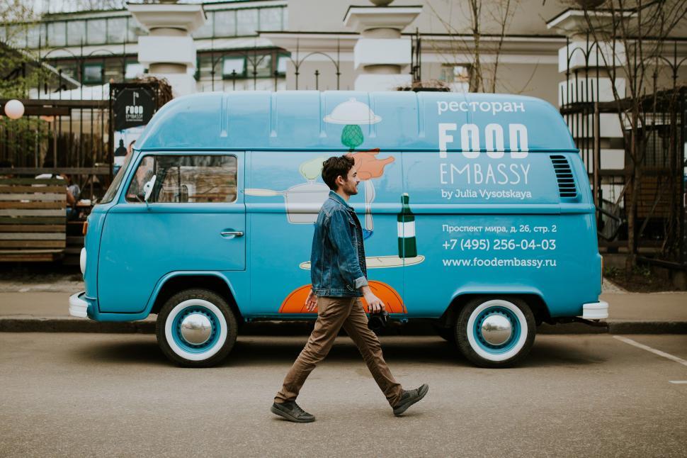 Free Image of Man Walking Across Parking Lot Next to Blue Van 