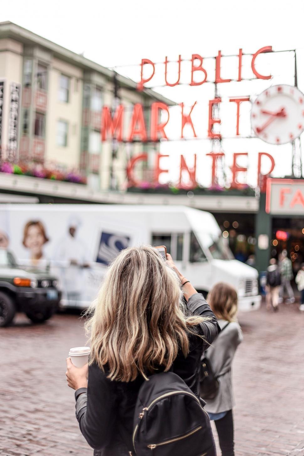 Free Image of Woman Taking Picture of Public Market 
