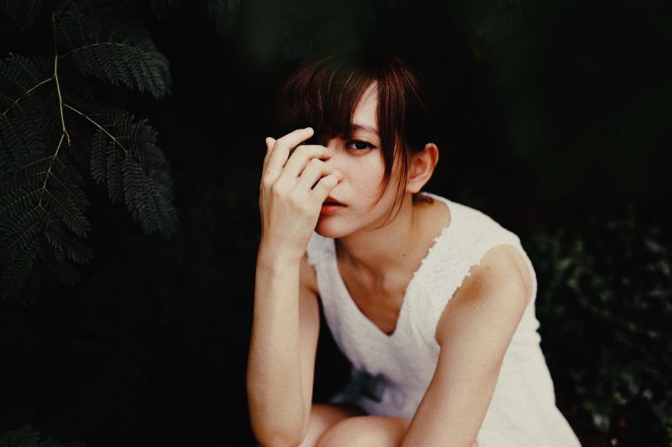 Free Image of Woman Sitting on Ground With Hand on Face 