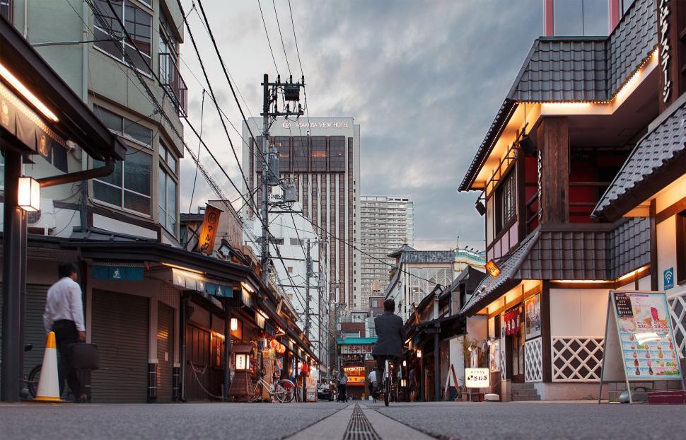 Free Image of Man Walking Down a Street Next to Tall Buildings 