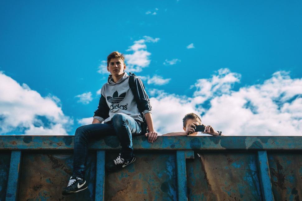 Free Image of Two Men Sitting on Top of Metal Rail 