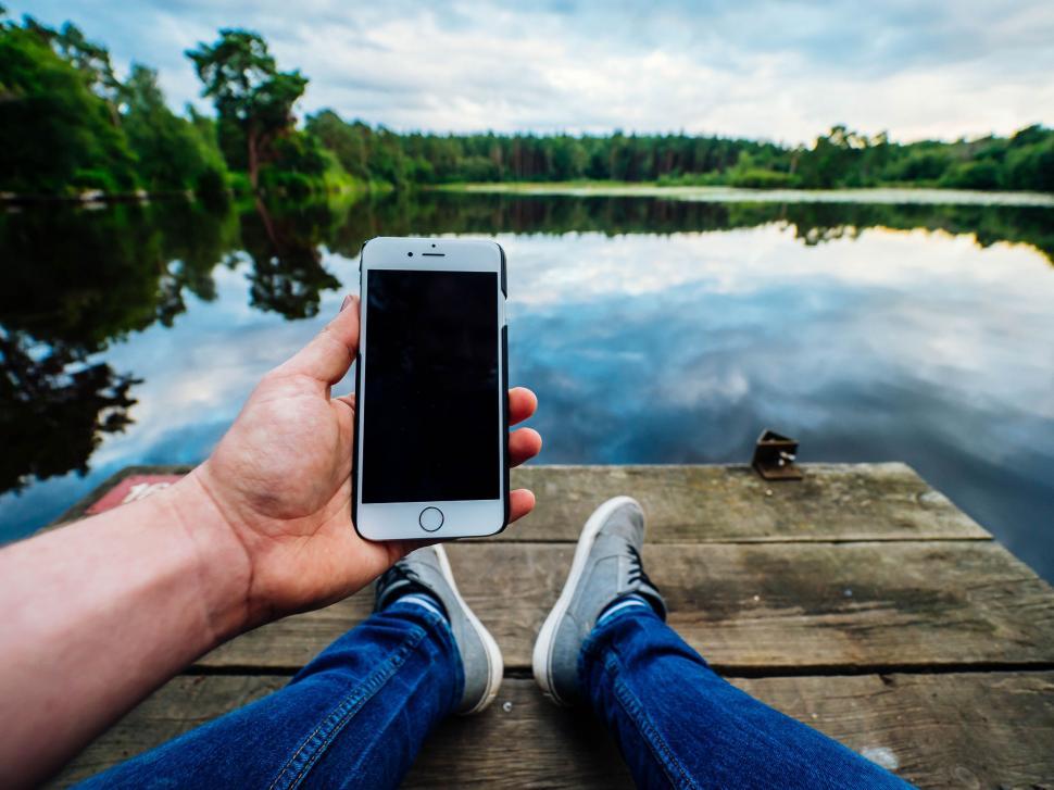 Free Image of Person Sitting on Dock Holding Cell Phone 