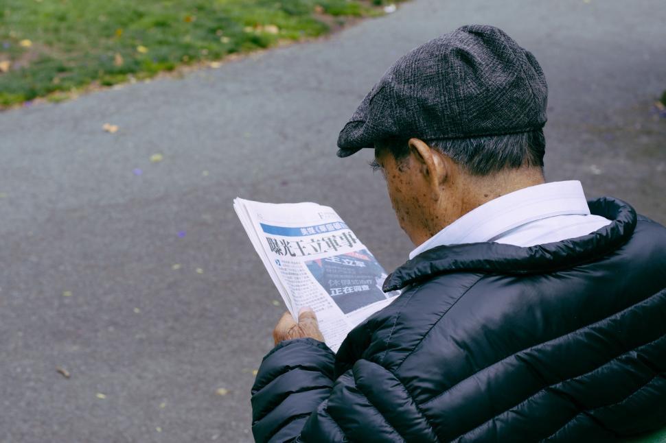 Free Image of Man Sitting on Bench Reading Newspaper 